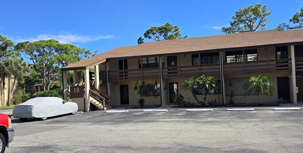 A two-story apartment building with a brown shingled roof and a parking lot in front — 10 QUAILS RUN BOULEVARD UNIT 1, ENGLEWOOD, FL