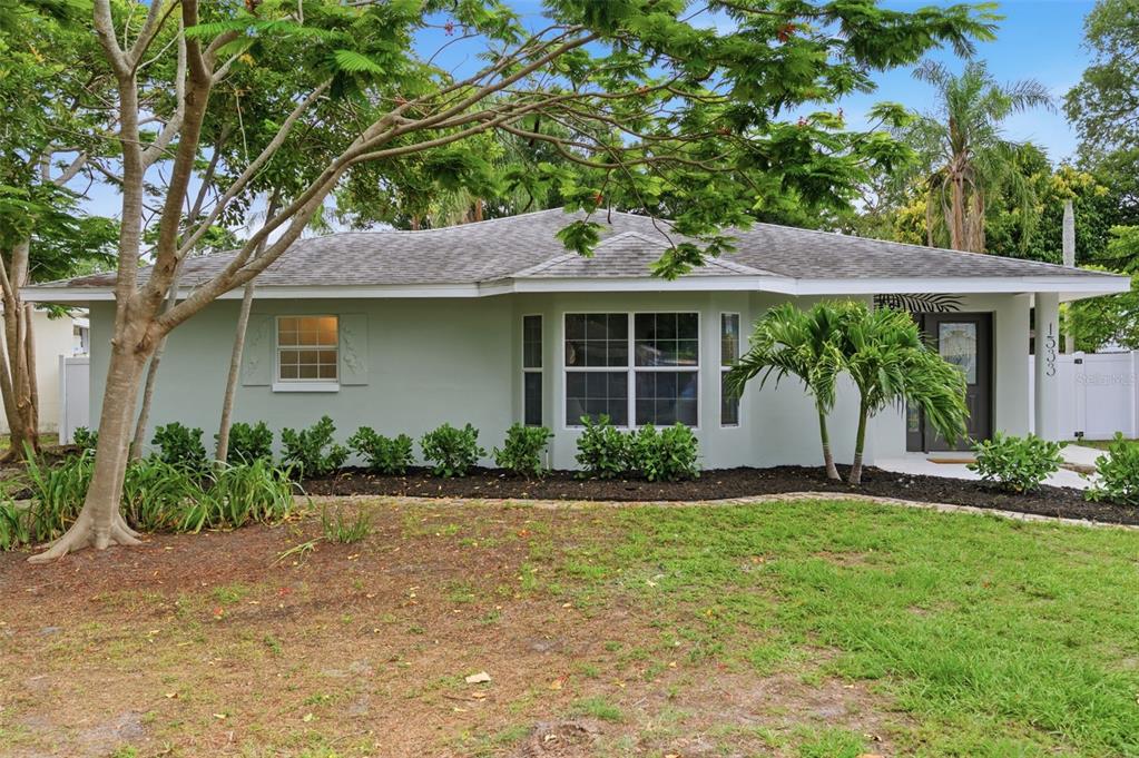 A single-story house with light green siding, a gray roof, and a landscaped front yard — 1533 SUFFOLK STREET N, ST PETERSBURG, FL