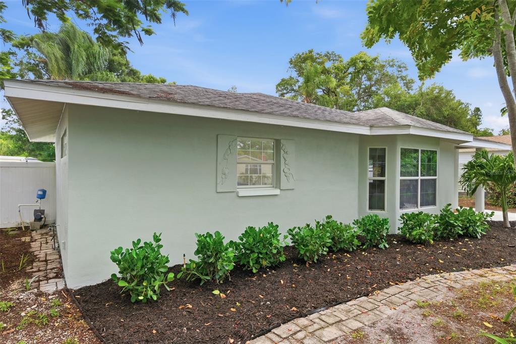 A light green house exterior with a shingled roof, a single window, and landscaping — 1533 SUFFOLK STREET N, ST PETERSBURG, FL