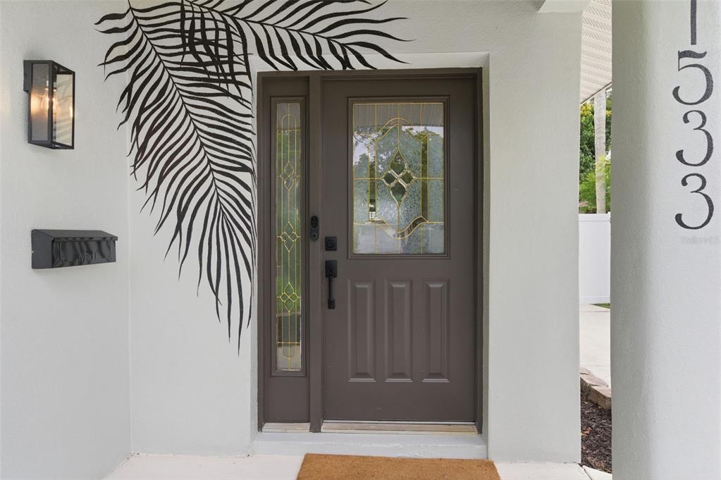 A brown front door with a side light and palm leaf wall art on the exterior — 1533 SUFFOLK STREET N, ST PETERSBURG, FL