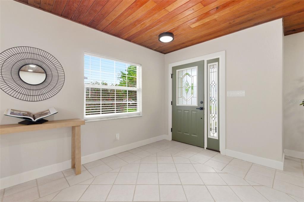 An entryway features a wood-paneled ceiling, tiled floor, sage green front door, and console table — 1533 SUFFOLK STREET N, ST PETERSBURG, FL