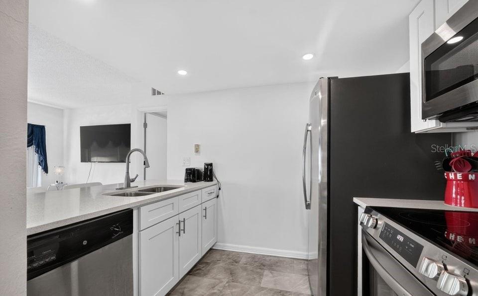A kitchen features white cabinets, stainless steel appliances, and a sink with a gooseneck faucet — 3600 S OCEAN SHORE BOULEVARD UNIT 111, FLAGLER BEACH, FL