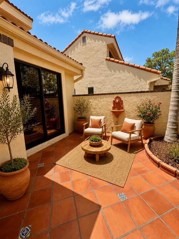 A patio with terracotta tiles, two wooden chairs, a small table, and a wall fountain — 5312 HUNTINGWOOD COURT UNIT 39, SARASOTA, FL
