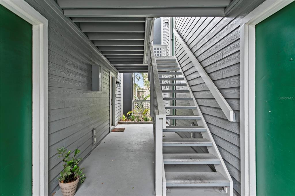 An outdoor stairwell leads to an upper level between two green doors on gray siding — 606 S ALBANY AVENUE UNIT 17, TAMPA, FL