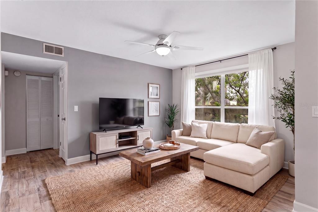 A living room features a sectional sofa, wooden coffee table, television, and light wood flooring — 606 S ALBANY AVENUE UNIT 17, TAMPA, FL