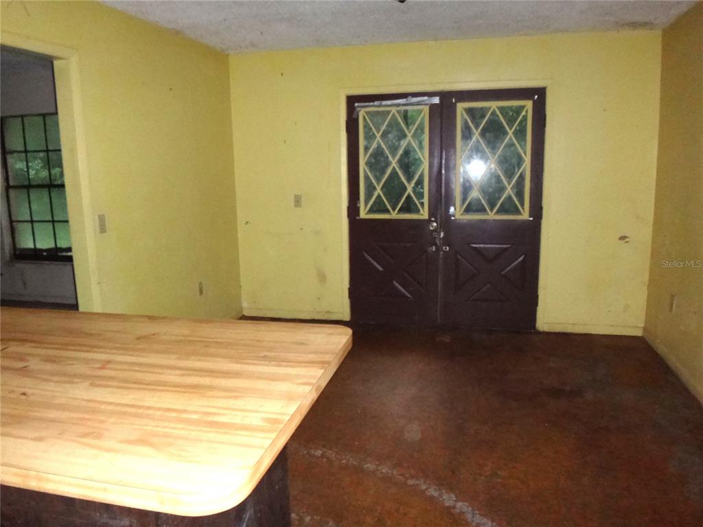 A room with yellow walls, a wooden countertop, and dark double doors with glass panes — 7556 23RD STREET, ZEPHYRHILLS, FL