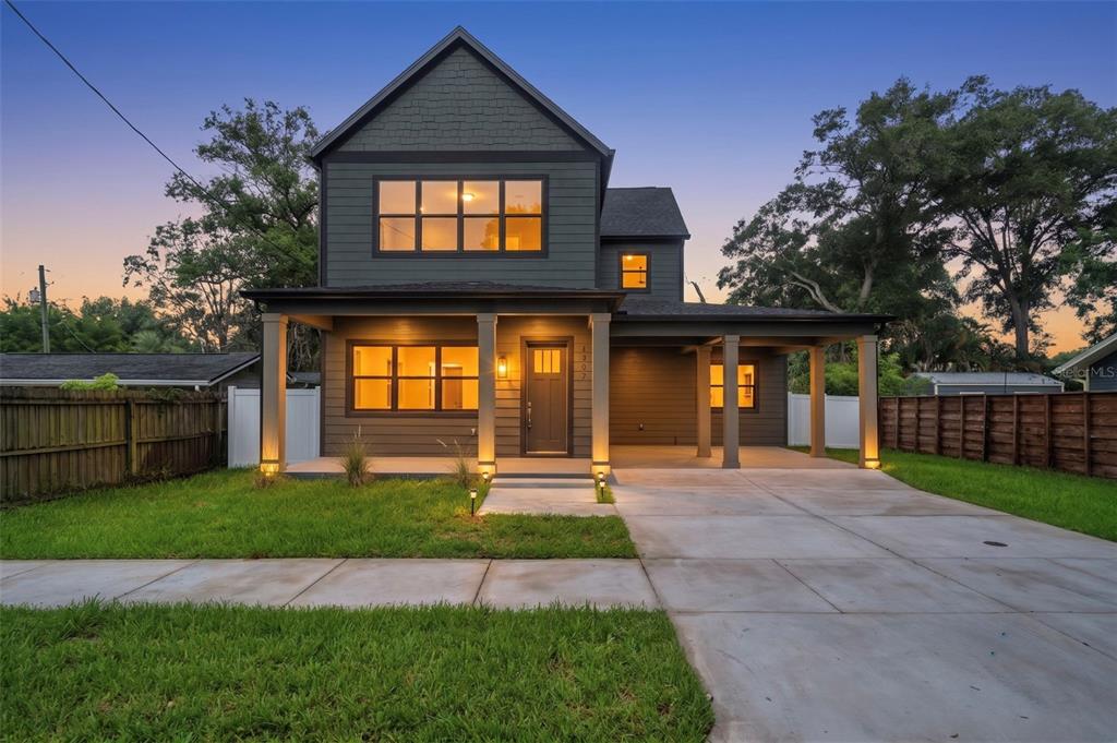 A two-story house with dark siding, a front porch, and a concrete driveway at dusk — 6606 N 9TH STREET, TAMPA, FL