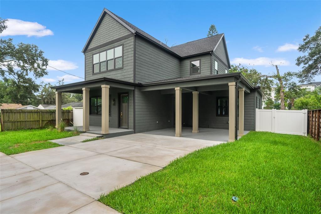 A two-story house with dark gray siding, a covered porch, and an attached carport — 6606 N 9TH STREET, TAMPA, FL