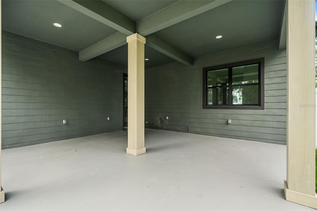 A covered outdoor patio features dark horizontal siding, recessed lighting, and two light-colored support columns — 6606 N 9TH STREET, TAMPA, FL