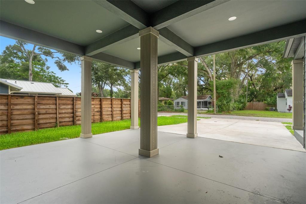 A covered concrete patio features four support columns and a view of a grassy yard — 6606 N 9TH STREET, TAMPA, FL