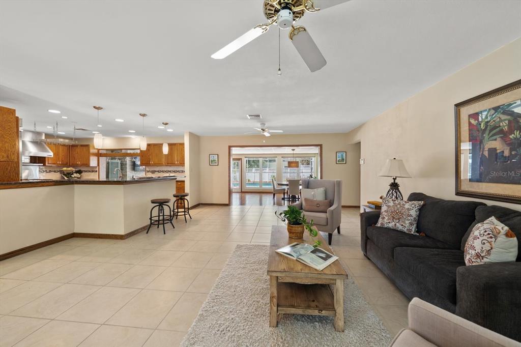 A living room with tile floors, a dark sofa, and an open kitchen area — 802 ALLAMANDA DRIVE, LARGO, FL