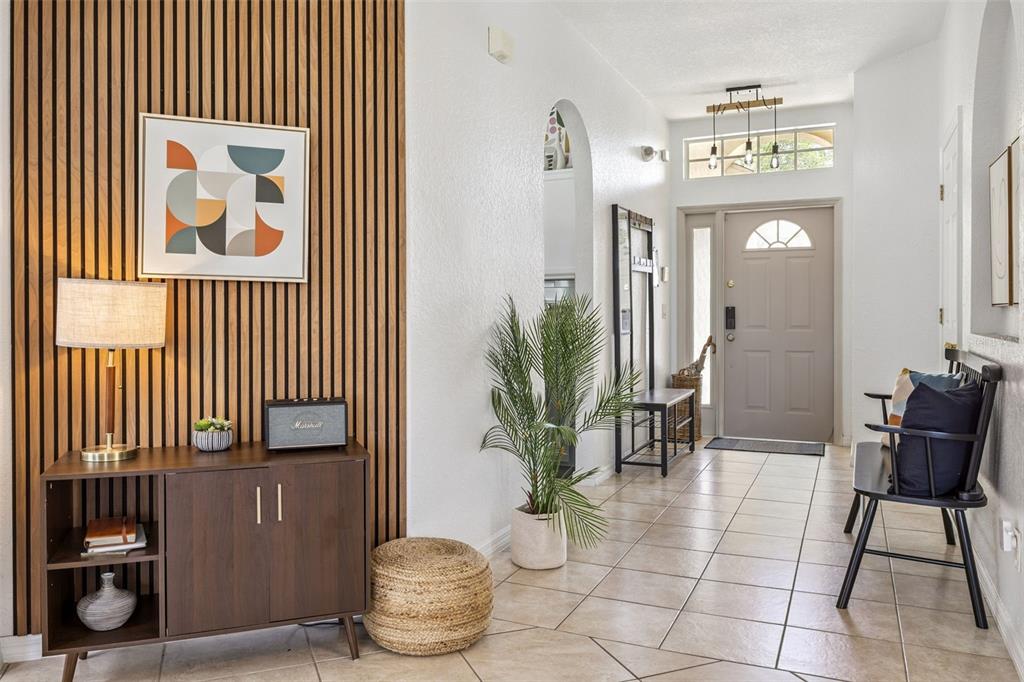 An entryway features a wood-slat accent wall, a console table, a plant, and tile flooring — 147 TROON CIRCLE, DAVENPORT, FL
