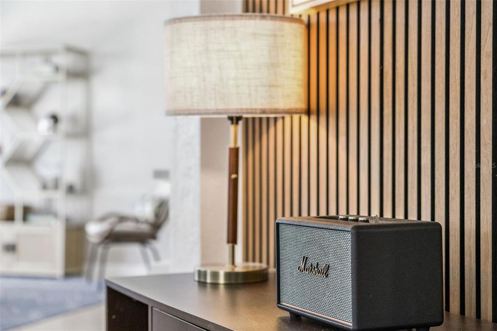A Marshall speaker sits on a dark surface next to a lamp against wood-slatted walls — 147 TROON CIRCLE, DAVENPORT, FL