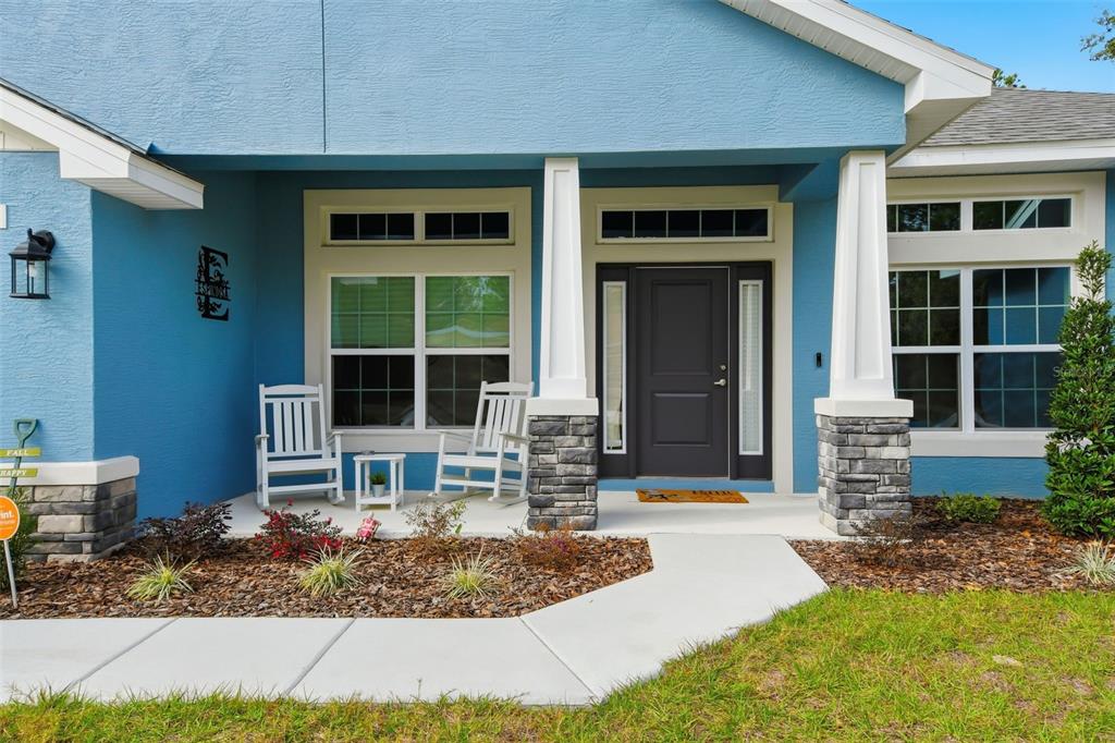 A blue house exterior features a covered front porch with two white rocking chairs — 14351 CAROLINA CHICKADEE ROAD, WEEKI WACHEE, FL