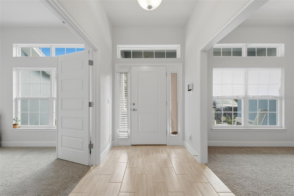 A bright entryway features light-colored tile flooring, a white front door, and carpeted adjacent rooms — 14351 CAROLINA CHICKADEE ROAD, WEEKI WACHEE, FL