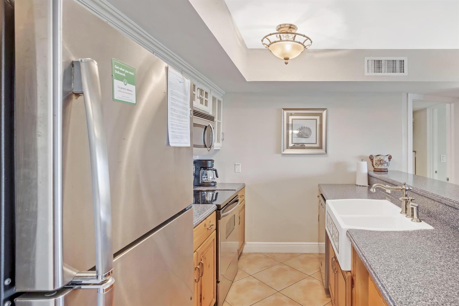 A kitchen features stainless steel appliances, wood cabinets, granite countertops, and a farmhouse sink — 4303 Marina Villas Drive, FL 33050, FL
