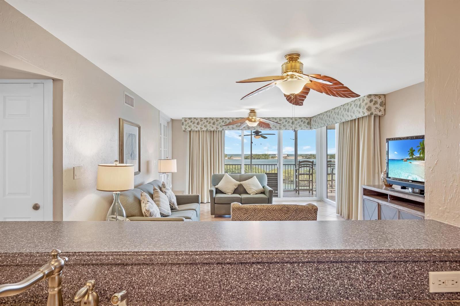 A living room with a view of the water features ceiling fans and neutral furniture — 4303 Marina Villas Drive, FL 33050, FL