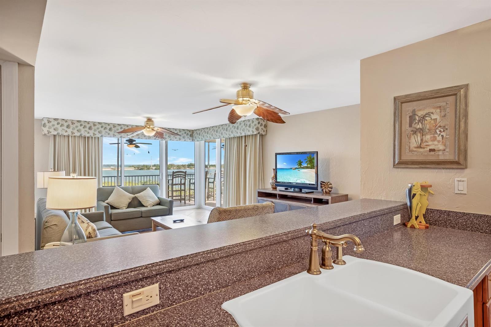 A kitchen sink overlooks a living area with a view of the water and balcony — 4303 Marina Villas Drive, FL 33050, FL