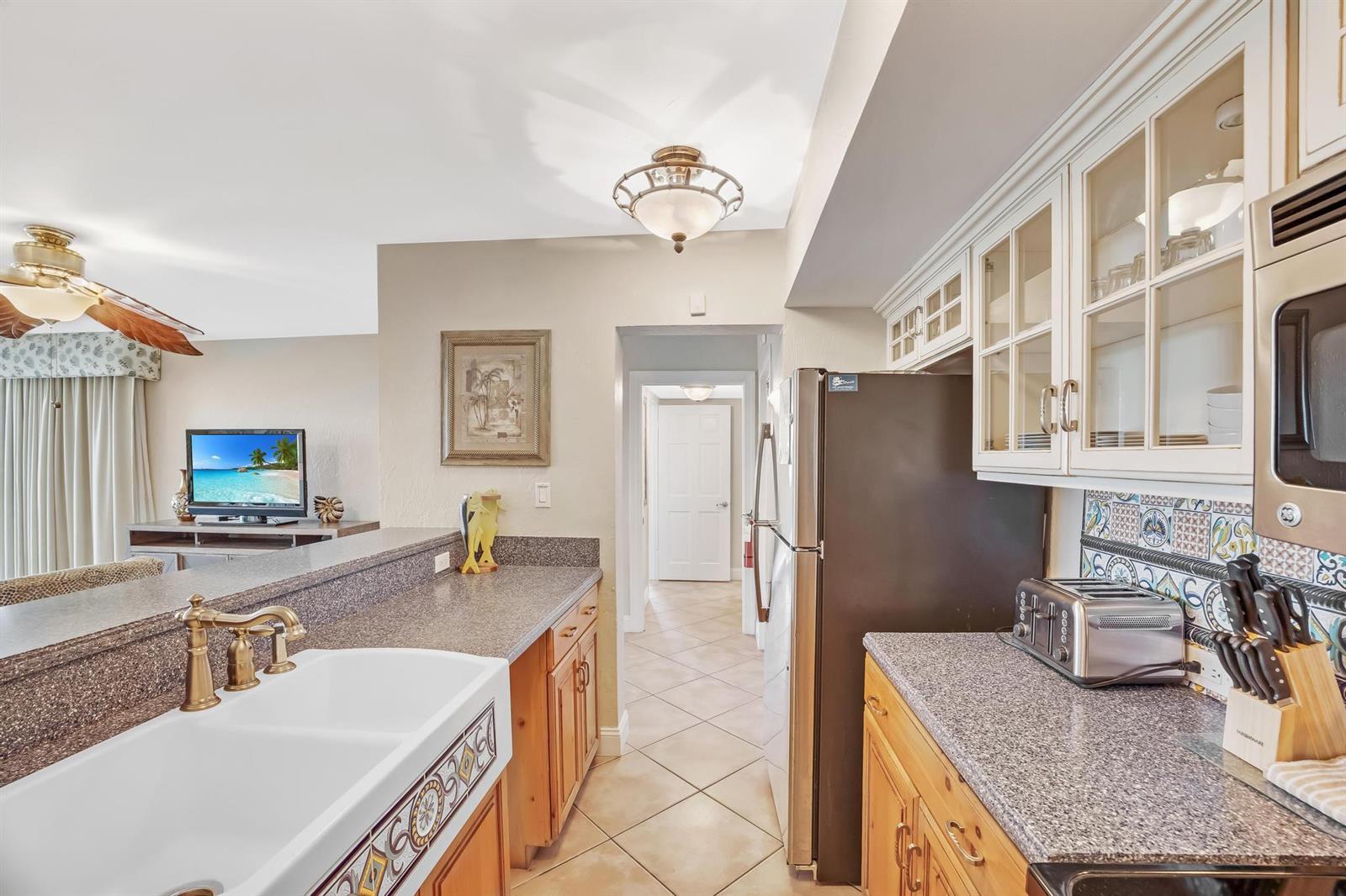 A kitchen features granite countertops, a farmhouse sink, wooden cabinets, and a tiled backsplash — 4303 Marina Villas Drive, FL 33050, FL