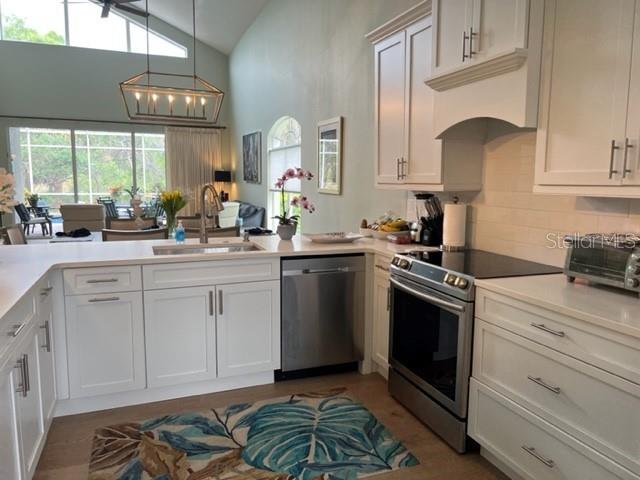 A kitchen with white cabinetry, stainless steel appliances, and a large island overlooks a patio — 8784 PEBBLE CREEK LANE, SARASOTA, FL