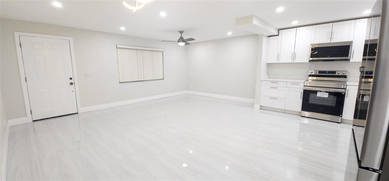 A bright, open-concept kitchen and living area features white cabinetry, stainless appliances, and tile flooring — 343 Normandy # 343, Delray Beach FL 33484, DELRAY BEACH, FL