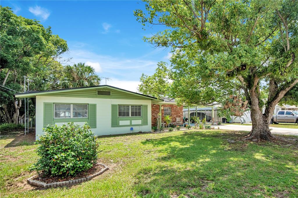 A single-story house with green trim and a brick facade sits behind a large tree — 309 VIHLEN ROAD, SANFORD, FL
