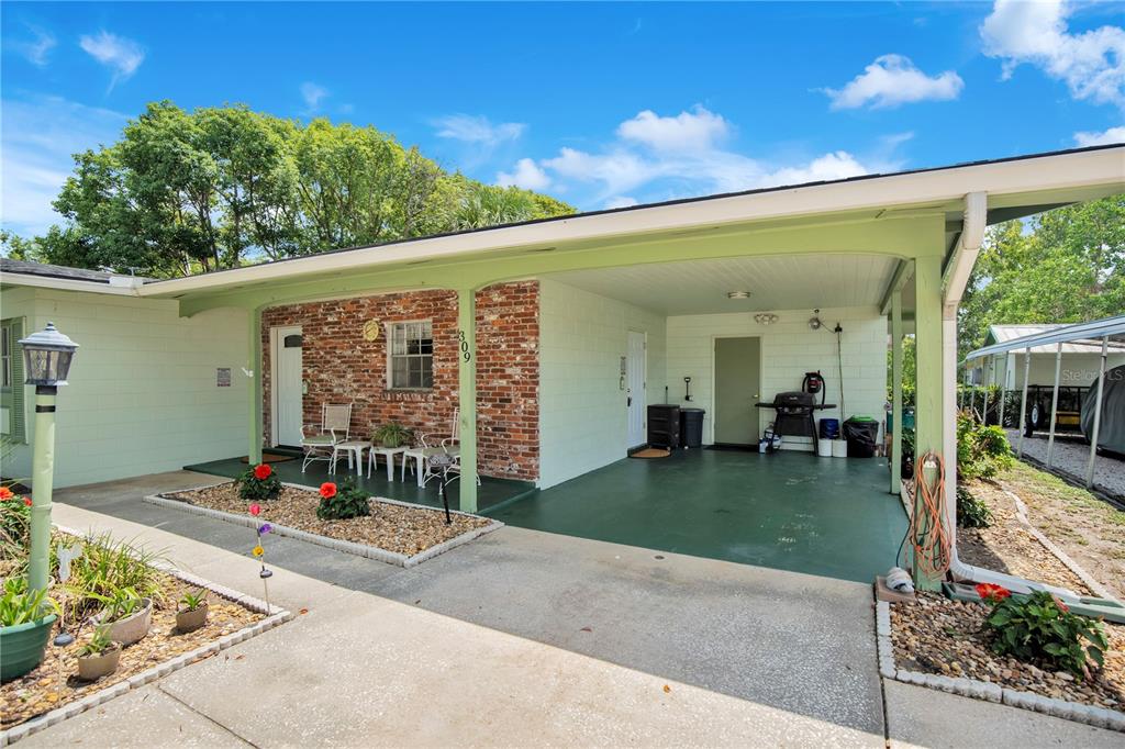 A light green house with a brick facade, a covered carport, and a front patio — 309 VIHLEN ROAD, SANFORD, FL
