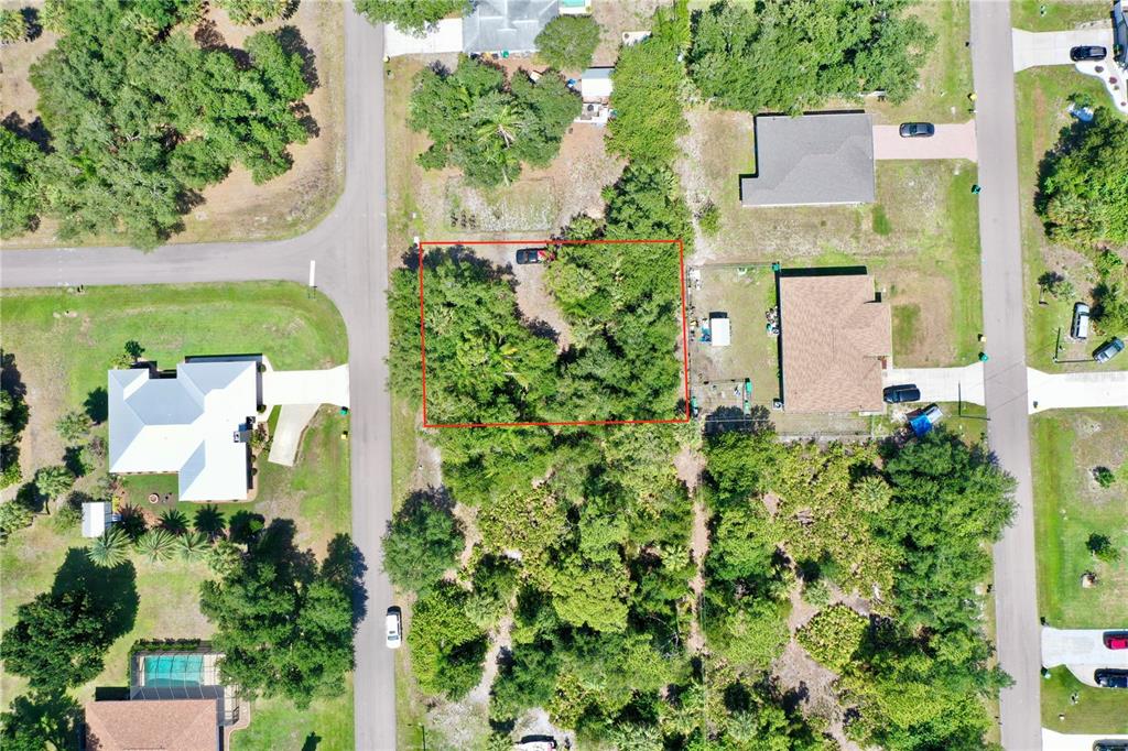 An aerial view shows a rectangular, tree-covered vacant lot outlined in red between two houses — 22324 STATE AVENUE, PORT CHARLOTTE, FL