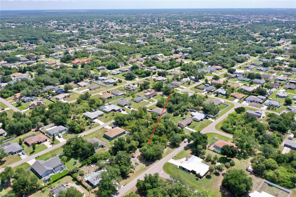 An aerial view shows a vacant, tree-covered residential lot marked by a red arrow — 22324 STATE AVENUE, PORT CHARLOTTE, FL