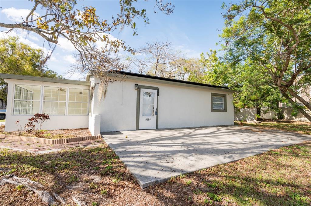 A white house exterior features a concrete patio, a glass-paneled door, and a sunroom — 6699 78TH AVENUE N, PINELLAS PARK, FL