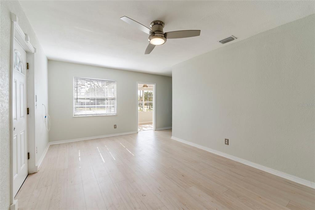 A bright room with light wood-look flooring, a ceiling fan, and a doorway to outside — 6699 78TH AVENUE N, PINELLAS PARK, FL