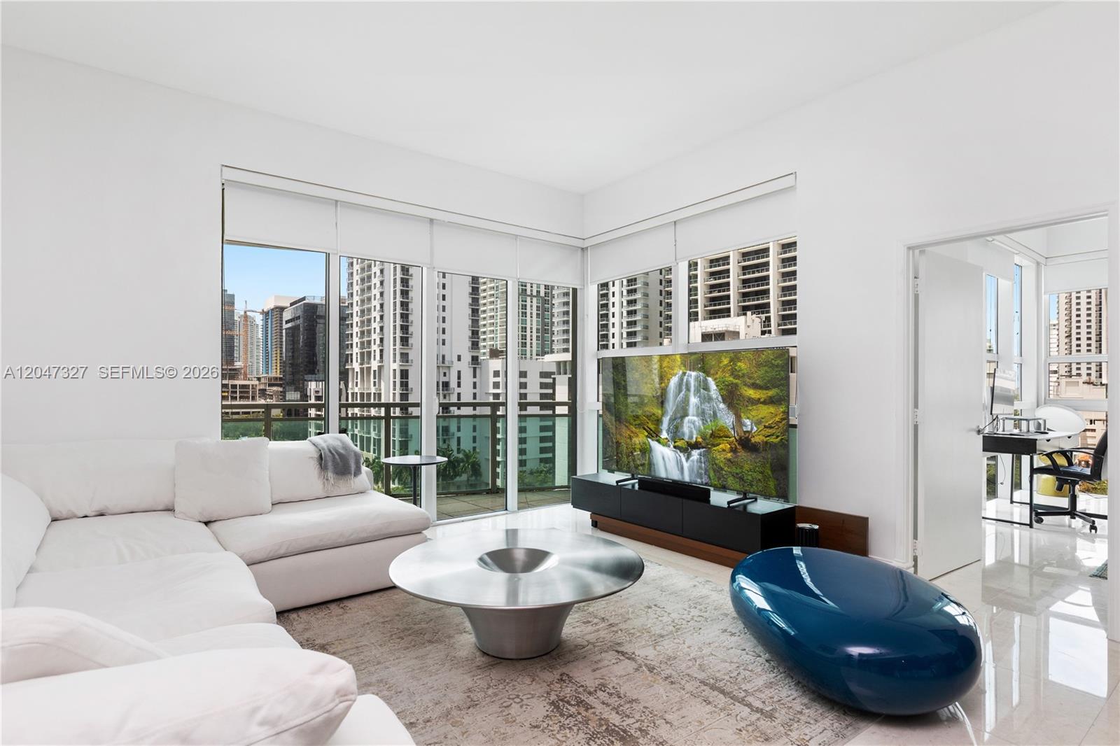 A modern living room features a white sectional sofa, metallic coffee table, and floor-to-ceiling windows — 951 Brickell Ave # 1011, Miami FL 33131, MIAMI, FL