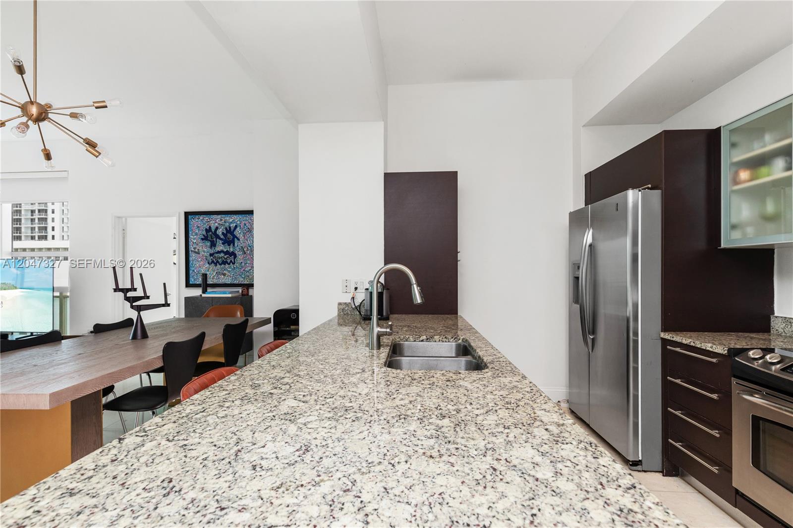 A kitchen features a long granite island, stainless steel appliances, and dark wood cabinetry — 951 Brickell Ave # 1011, Miami FL 33131, MIAMI, FL