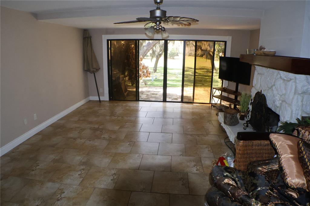 A living room features tile flooring, a ceiling fan, sliding glass doors, and a fireplace — 3003 FINSTERWALD DRIVE UNIT 3, TITUSVILLE, FL