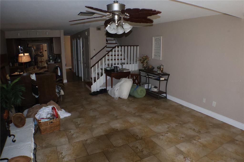 A living room features tile flooring, a ceiling fan, and a staircase with white railings — 3003 FINSTERWALD DRIVE UNIT 3, TITUSVILLE, FL