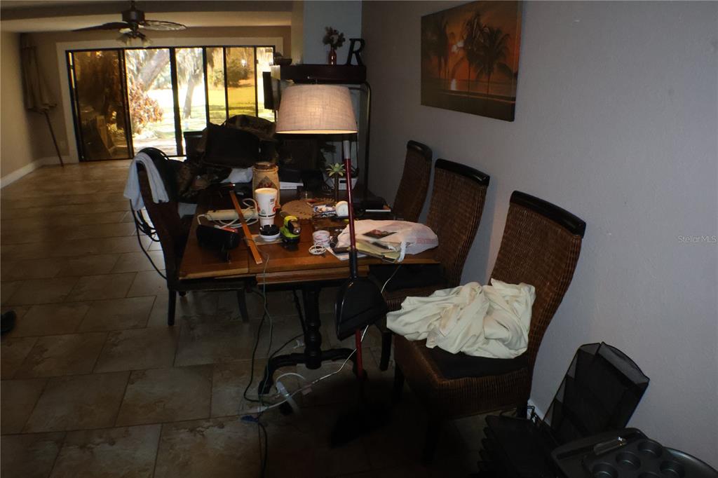 A dining area features a wooden table with chairs, a floor lamp, and tile flooring — 3003 FINSTERWALD DRIVE UNIT 3, TITUSVILLE, FL
