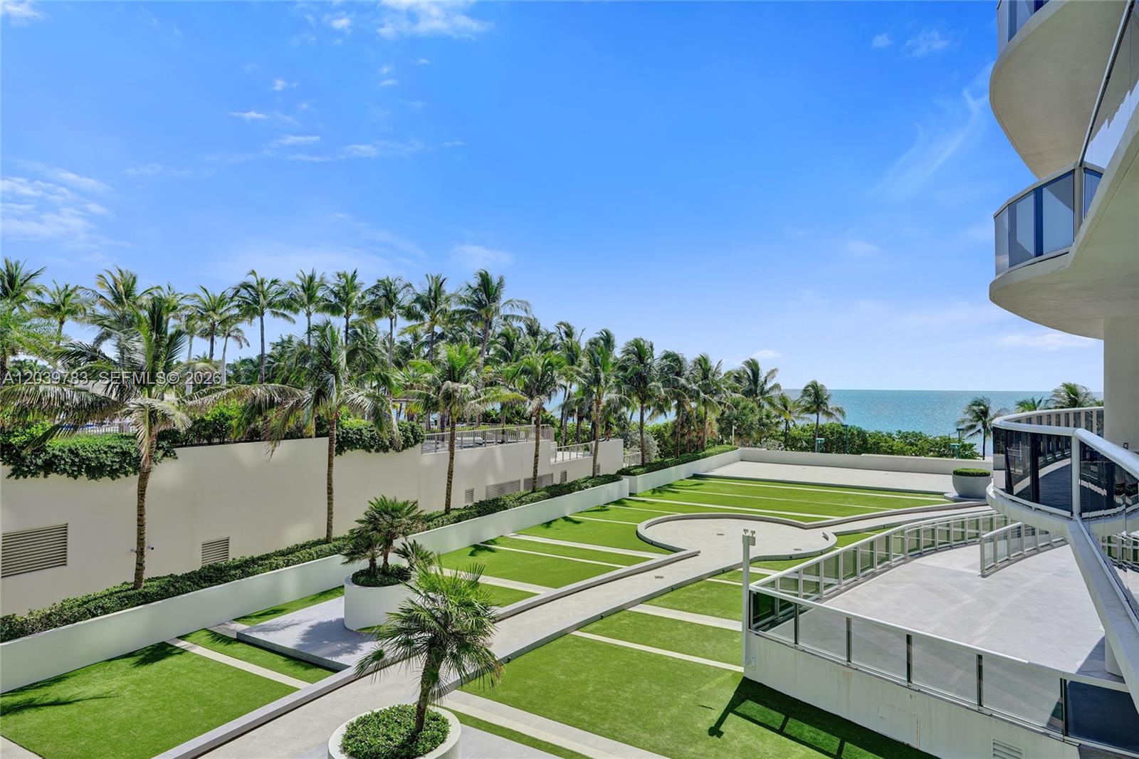 An elevated view of a landscaped terrace with artificial turf, palm trees, and ocean views — 9601 Collins Ave # 402, Bal Harbour FL 33154, BAL HARBOUR, FL