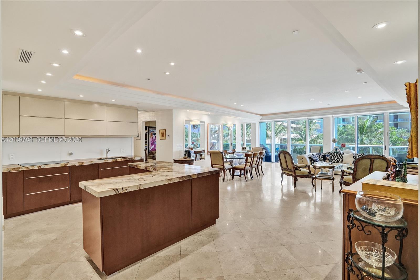 An open-concept kitchen and living area features marble countertops, dark wood cabinetry, and tile flooring — 9601 Collins Ave # 402, Bal Harbour FL 33154, BAL HARBOUR, FL