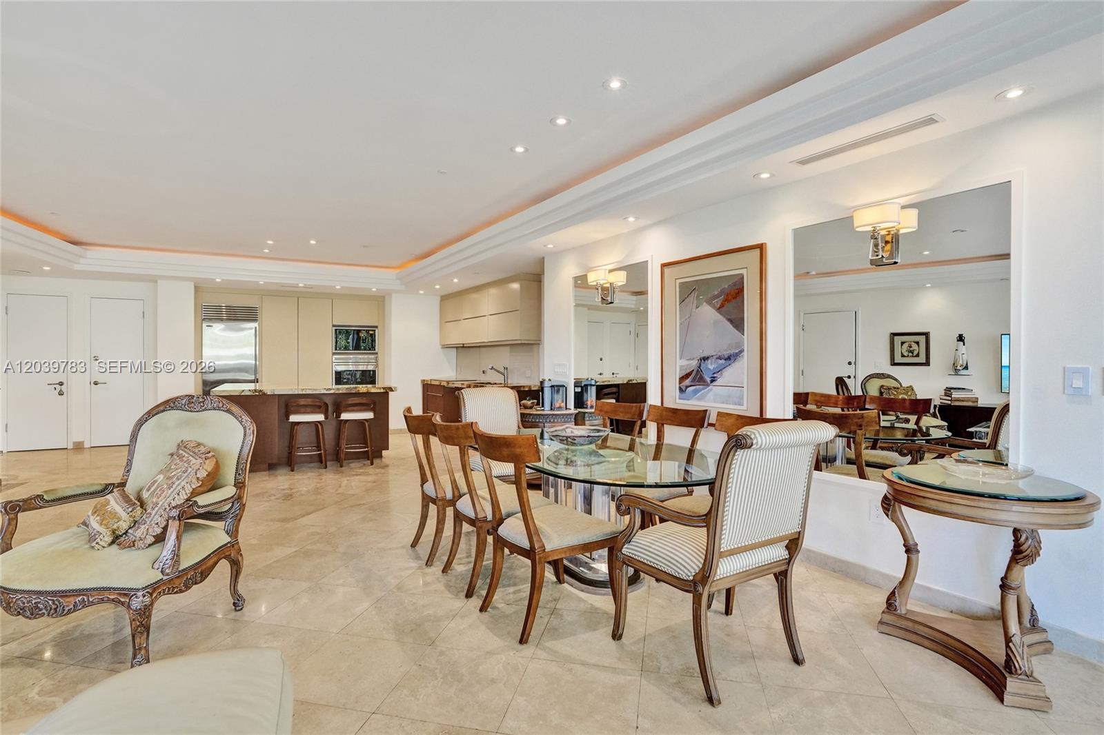 A dining area with a glass table and striped chairs sits beside an open kitchen — 9601 Collins Ave # 402, Bal Harbour FL 33154, BAL HARBOUR, FL