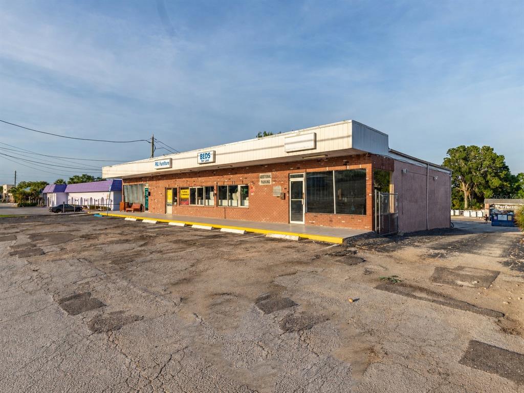 A single-story commercial building with a brick facade and a large, worn asphalt parking lot — 9933 SEMINOLE BOULEVARD, SEMINOLE, FL