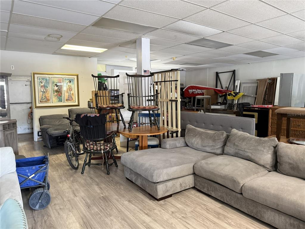 A room with a gray sectional sofa, wooden chairs, a bicycle, and a drop ceiling — 9933 SEMINOLE BOULEVARD, SEMINOLE, FL