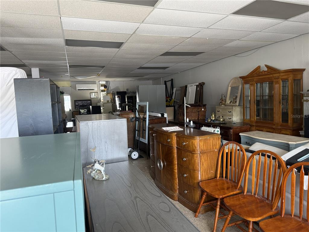 A cluttered room filled with various wooden furniture, chairs, and storage units under a drop ceiling — 9933 SEMINOLE BOULEVARD, SEMINOLE, FL