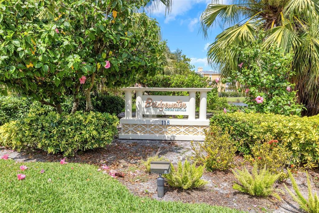 A sign for Bridgewater Luxury Rentals stands amidst lush landscaping and palm trees — 115 112TH AVENUE NE UNIT 703, ST PETERSBURG, FL
