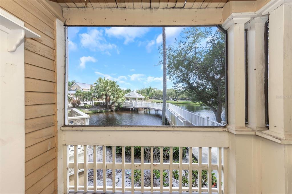 A screened-in porch overlooks a pond with a wooden footbridge and a gazebo — 115 112TH AVENUE NE UNIT 703, ST PETERSBURG, FL