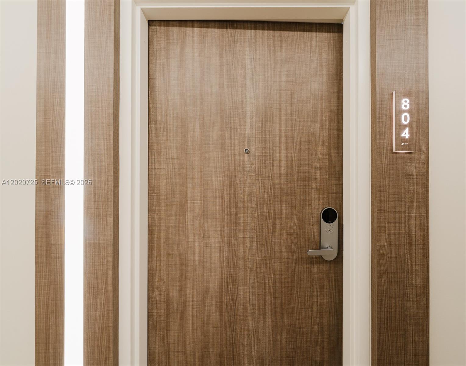 A wooden apartment door features a digital lock, a peephole, and a vertical room number sign — 2301 Collins Ave # 804, Miami Beach FL 33139, MIAMI BEACH, FL