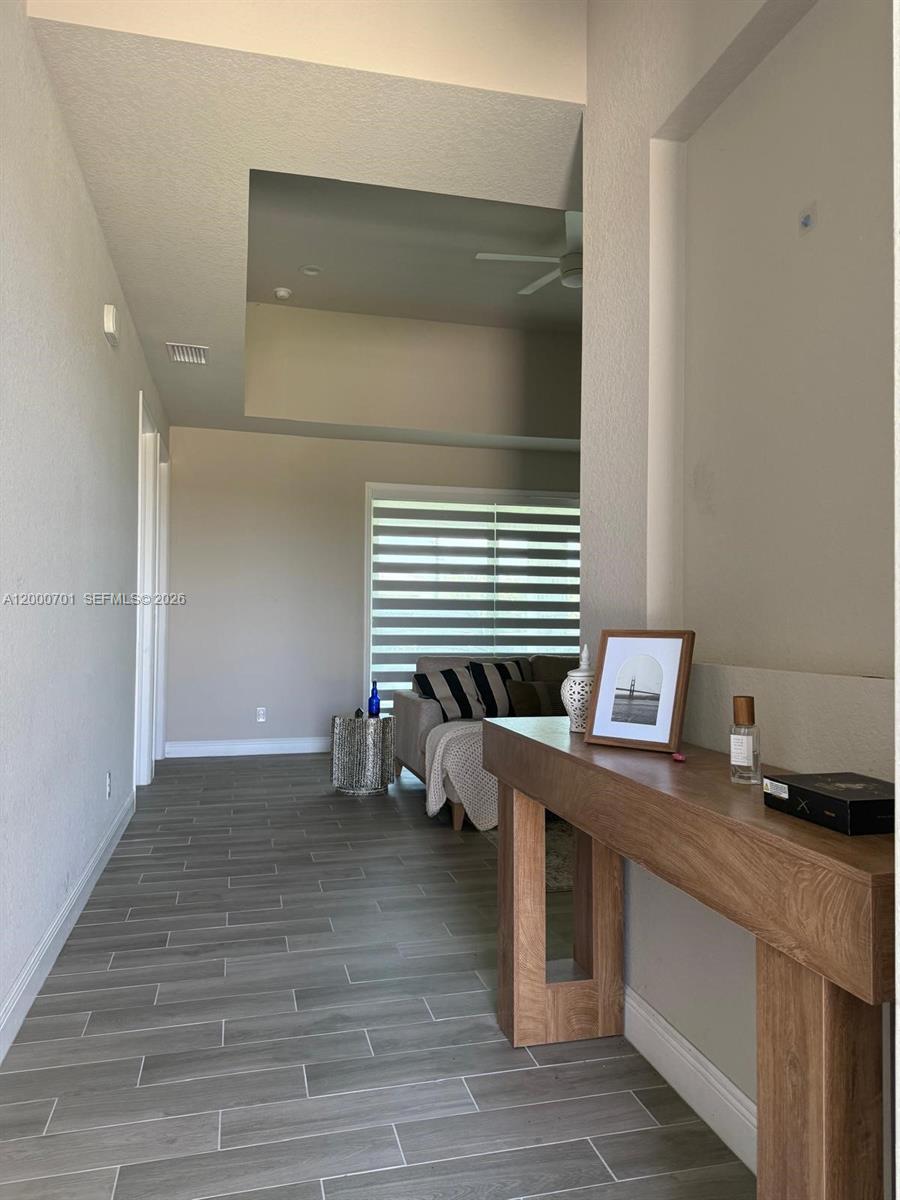 A hallway with wood-look tile flooring leads into a living room with high ceilings — 368 NEIGHBORLY RD, La Belle FL 33935, LA BELLE, FL