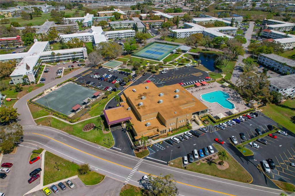 Aerial view of a multi-story building complex featuring a swimming pool, tennis courts, and parking — 2257 WORLD PARKWAY BOULEVARD W UNIT 61, CLEARWATER, FL