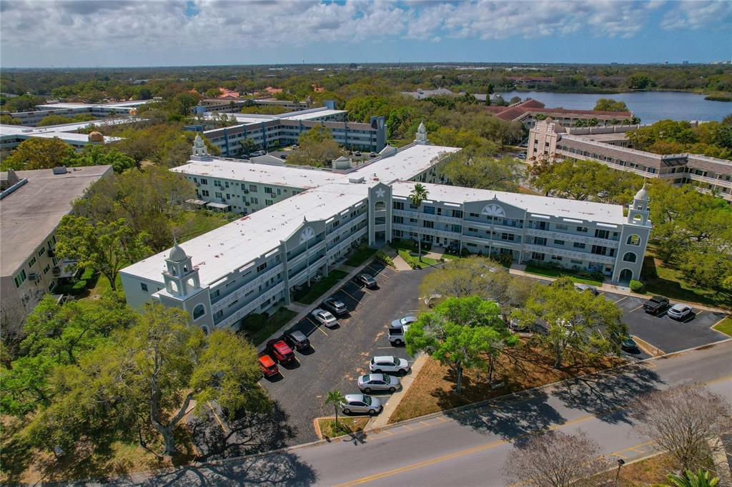 An aerial view shows a multi-story apartment complex with a white roof and parking lot — 2257 WORLD PARKWAY BOULEVARD W UNIT 61, CLEARWATER, FL