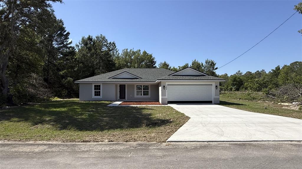 A single-story house with a gray exterior, a two-car garage, and a concrete driveway — 102 MALAUKA TRAIL, OCKLAWAHA, FL
