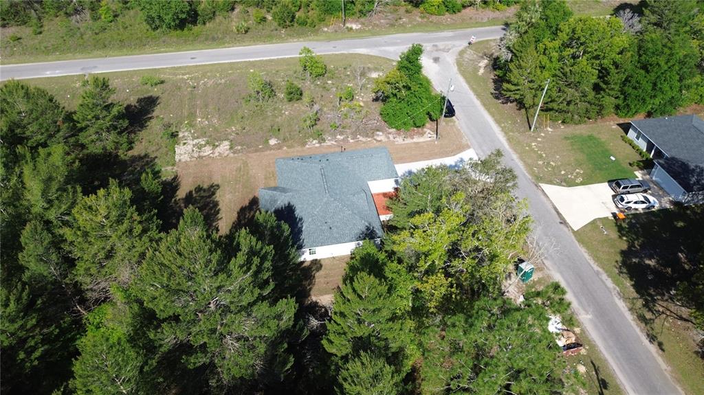 An aerial view shows a house with a dark roof surrounded by trees and roads — 102 MALAUKA TRAIL, OCKLAWAHA, FL